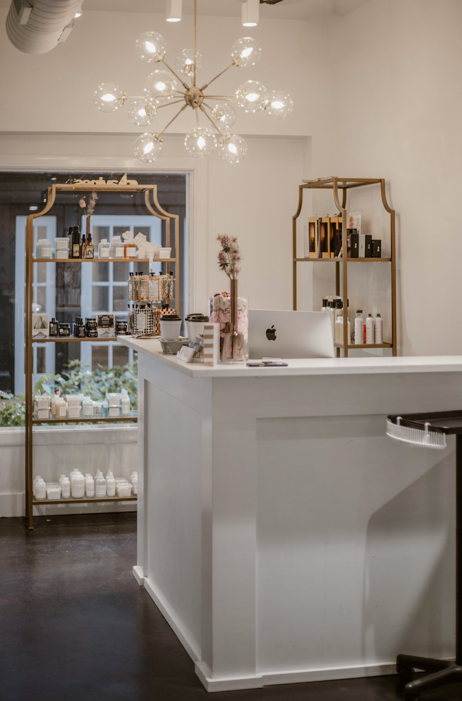Salon reception desk with laptop and beauty products.